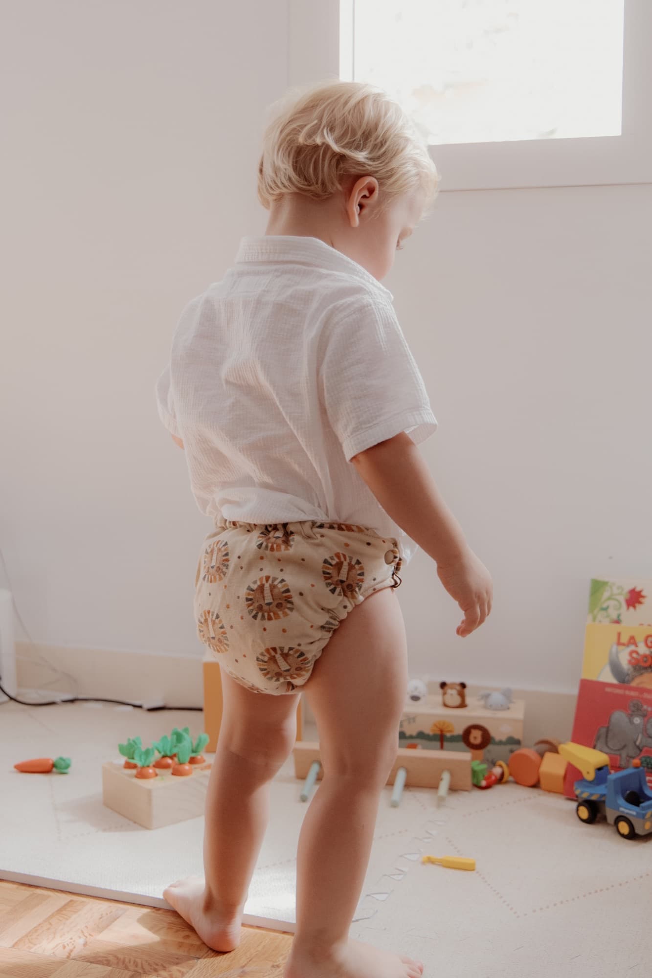 Toddler in a cloth diaper with lion print, standing
