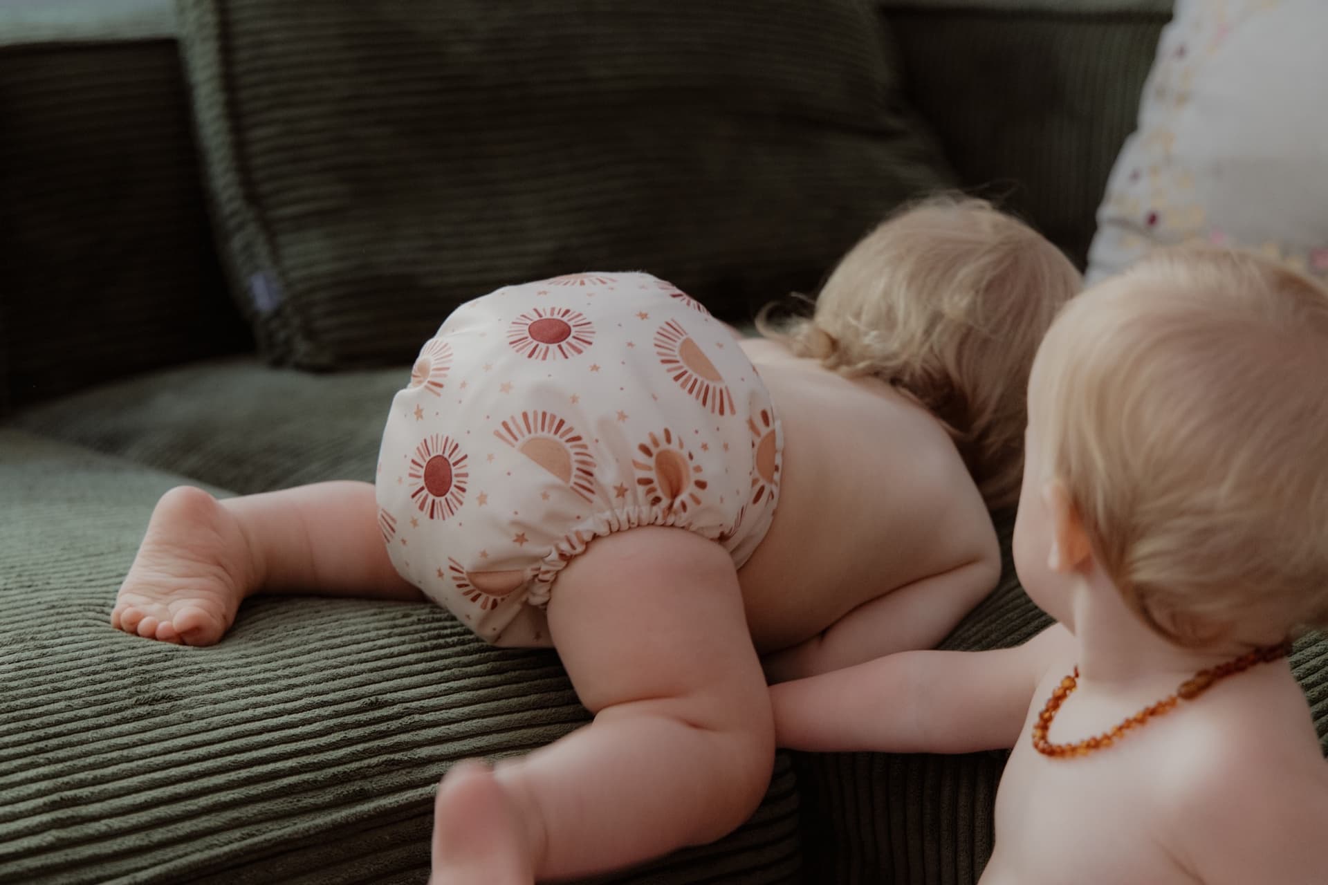 Two babies on a sofa, cloth diaper with sun pattern