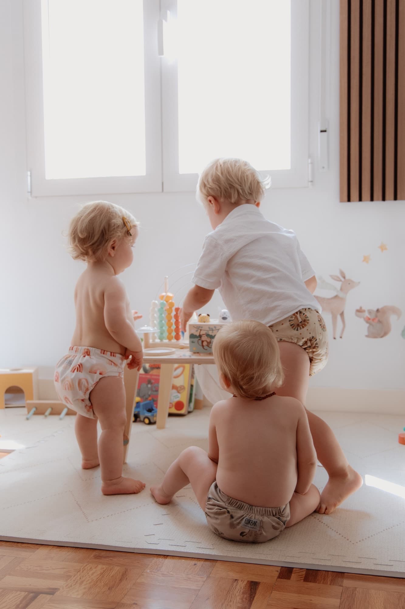 Three toddlers in different cloth diapers at a play table